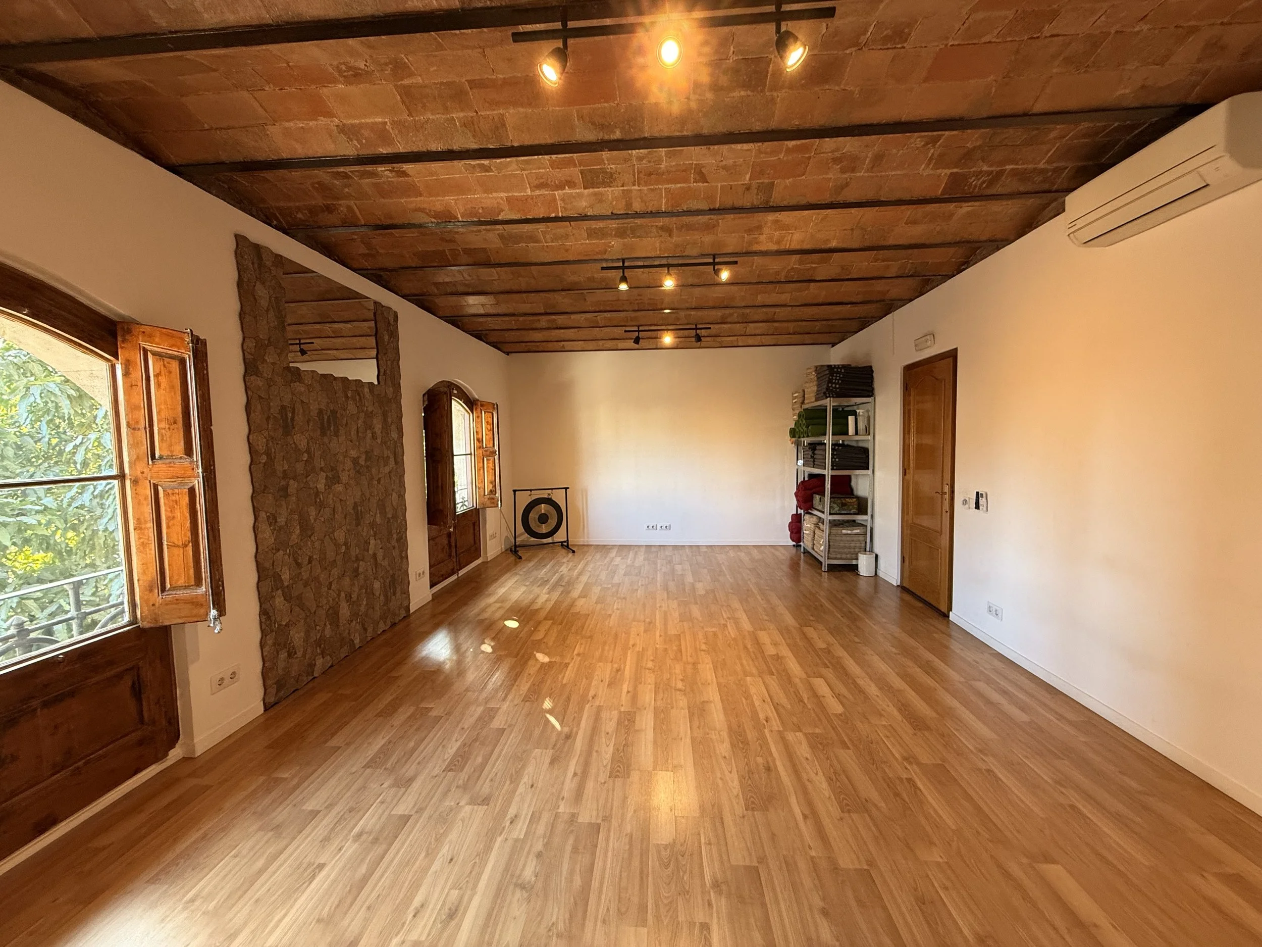 The Shala room with a vaulted brick ceiling, wooden floor and gong